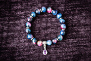 Multicolored beaded cremation bracelet with a silver charm on a dark textured background